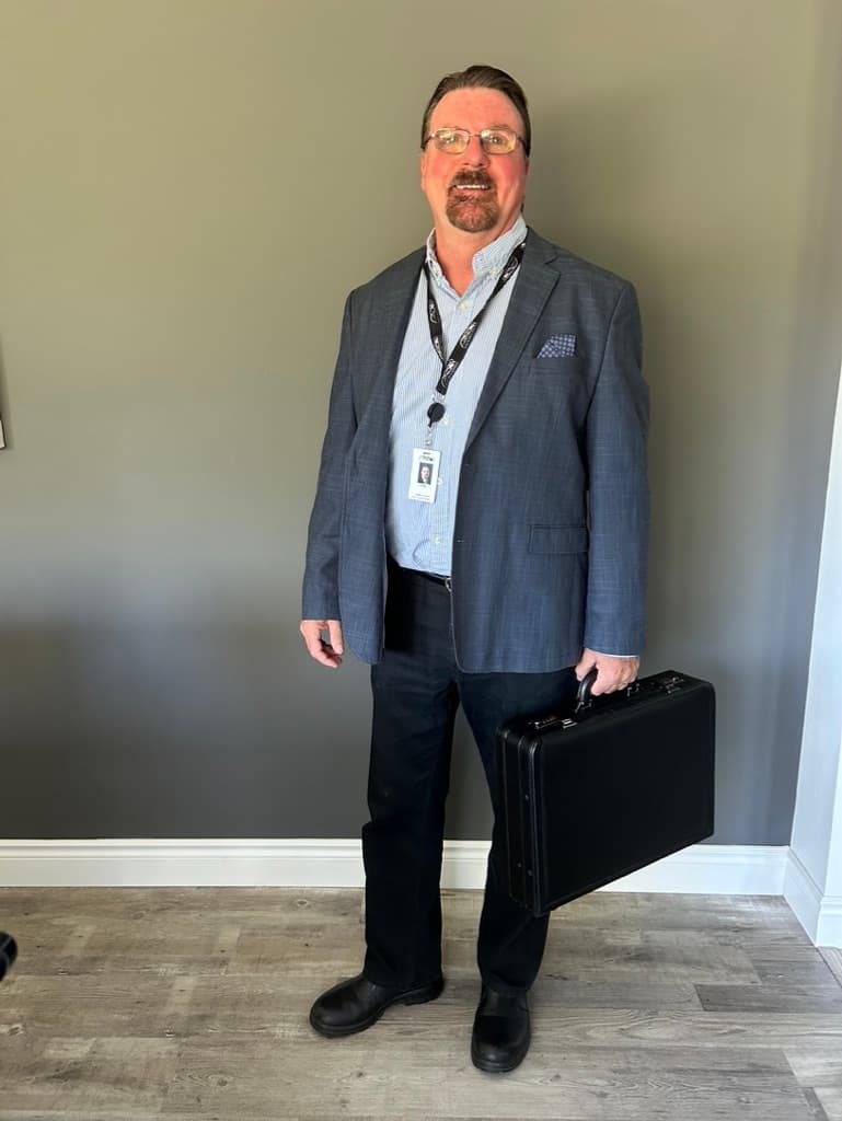 Doug Maskell in a suit holding a briefcase